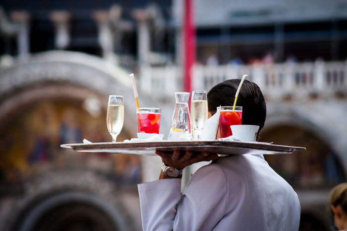 Waiter in NYC holding a tray with drinks, reflecting punk rock attitude. Waiter in NYC holding a tray with drinks, reflecting punk rock attitude.