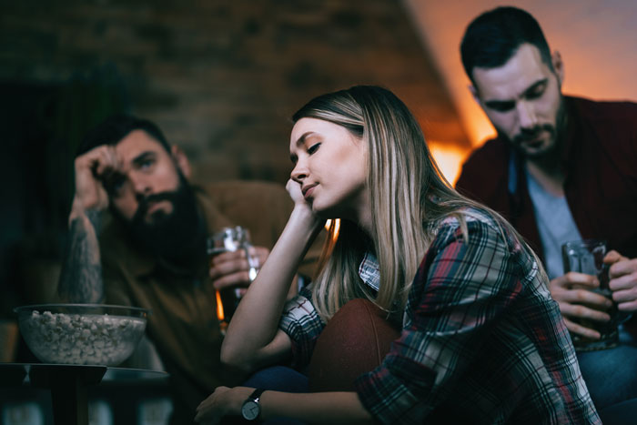 Three adults sitting together, looking contemplative, with a bowl of snacks on the table. Three adults sitting together, looking contemplative, with a bowl of snacks on the table.