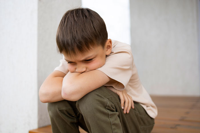A young boy sitting sadly, resting his head on folded arms, reflects custody issues. A young boy sitting sadly, resting his head on folded arms, reflects custody issues.