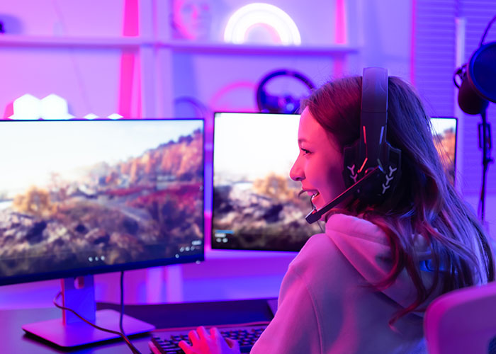 Woman gaming on a computer in a room with neon lights, wearing headphones. Woman gaming on a computer in a room with neon lights, wearing headphones.