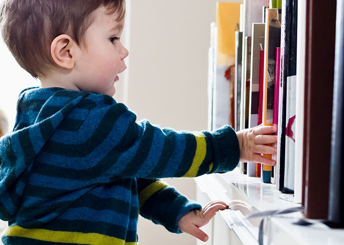Toddler reaching for books on a shelf, leading to family drama and damages. Toddler reaching for books on a shelf, leading to family drama and damages.