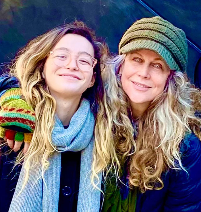 Two smiling women with long hair, one wearing a green knit hat and scarf, representing a former child star scenario. Two smiling women with long hair, one wearing a green knit hat and scarf, representing a former child star scenario.