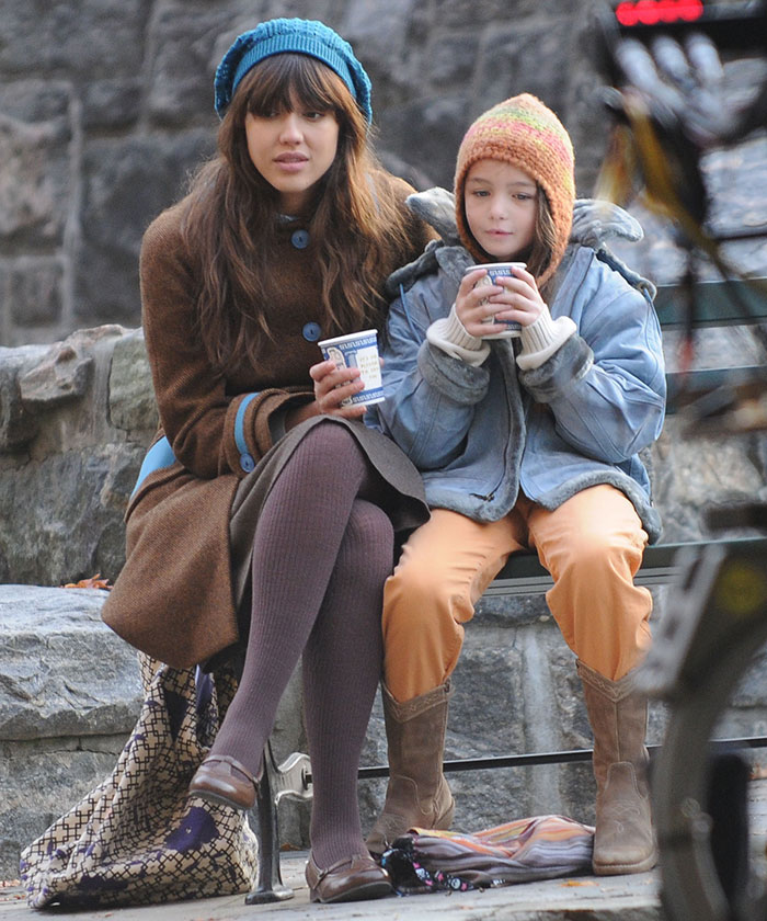 Two people sitting on a bench, wearing winter clothes, drinking from cups. Two people sitting on a bench, wearing winter clothes, drinking from cups.