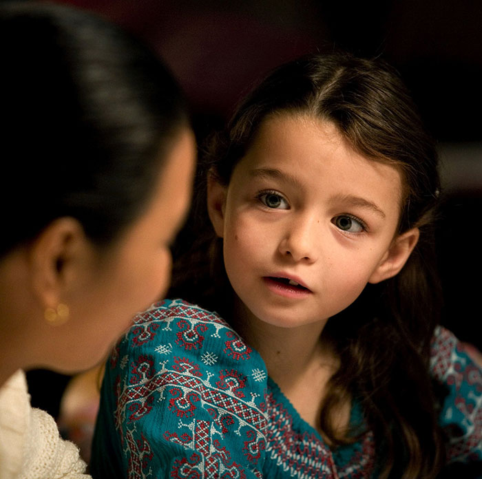 Former child star in a detailed blue dress, listening intently, with a curious expression. Former child star in a detailed blue dress, listening intently, with a curious expression.