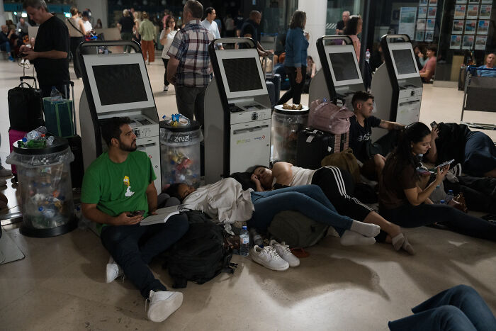 People waiting and resting near unused kiosks during a major blackout paralyzing activities for millions in Europe People waiting and resting near unused kiosks during a major blackout paralyzing activities for millions in Europe