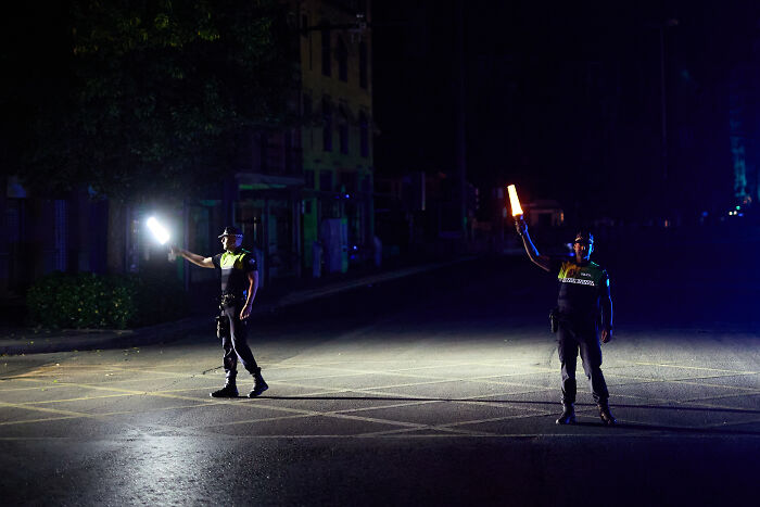 Two police officers directing traffic at night during a major blackout affecting millions in Europe. Two police officers directing traffic at night during a major blackout affecting millions in Europe.