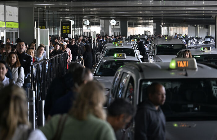 Crowded airport taxi queue with many people waiting, illustrating the impact of a major blackout paralyzing activities in Europe. Crowded airport taxi queue with many people waiting, illustrating the impact of a major blackout paralyzing activities in Europe.