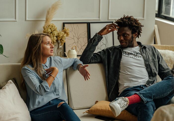 Stepdaughter and stepmom having intense holiday drama conversation while sitting on a couch in a living room. Stepdaughter and stepmom having intense holiday drama conversation while sitting on a couch in a living room.