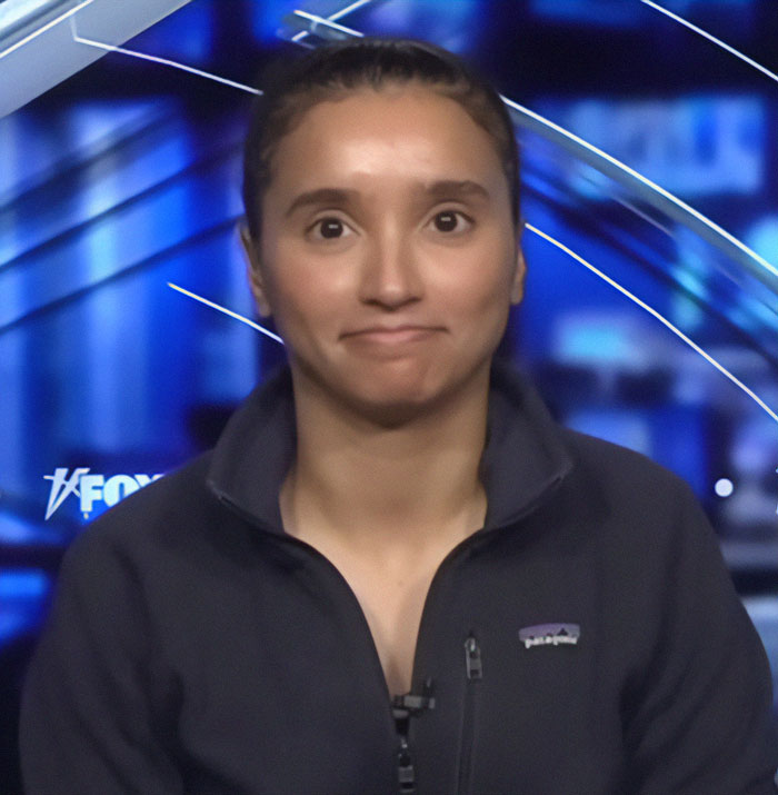 Trans athlete in studio interview, wearing a dark jacket, related to college's women's fencing team controversy. Trans athlete in studio interview, wearing a dark jacket, related to college's women's fencing team controversy.