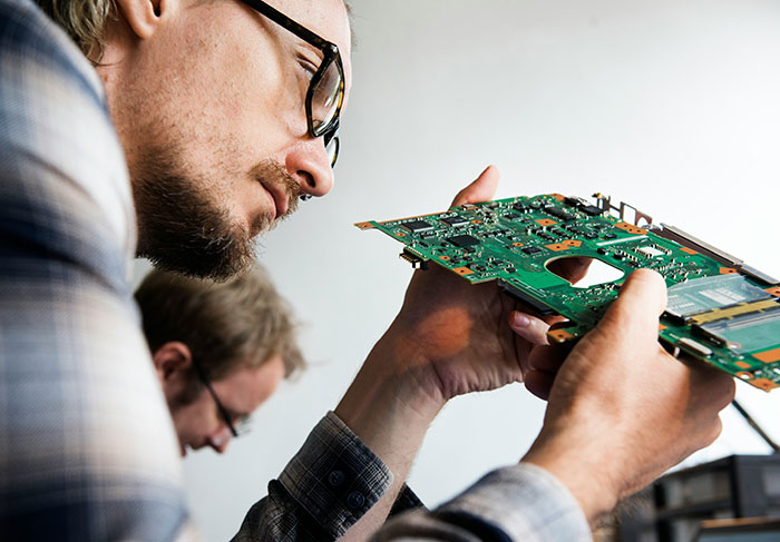 Technician examining a laptop motherboard closely, focusing on electronic components. Technician examining a laptop motherboard closely, focusing on electronic components.