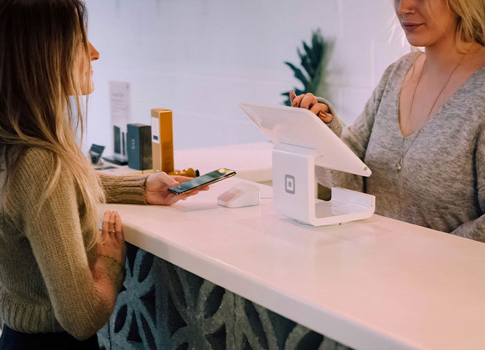 Woman at the counter with a smartphone near a point of sale device. Woman at the counter with a smartphone near a point of sale device.