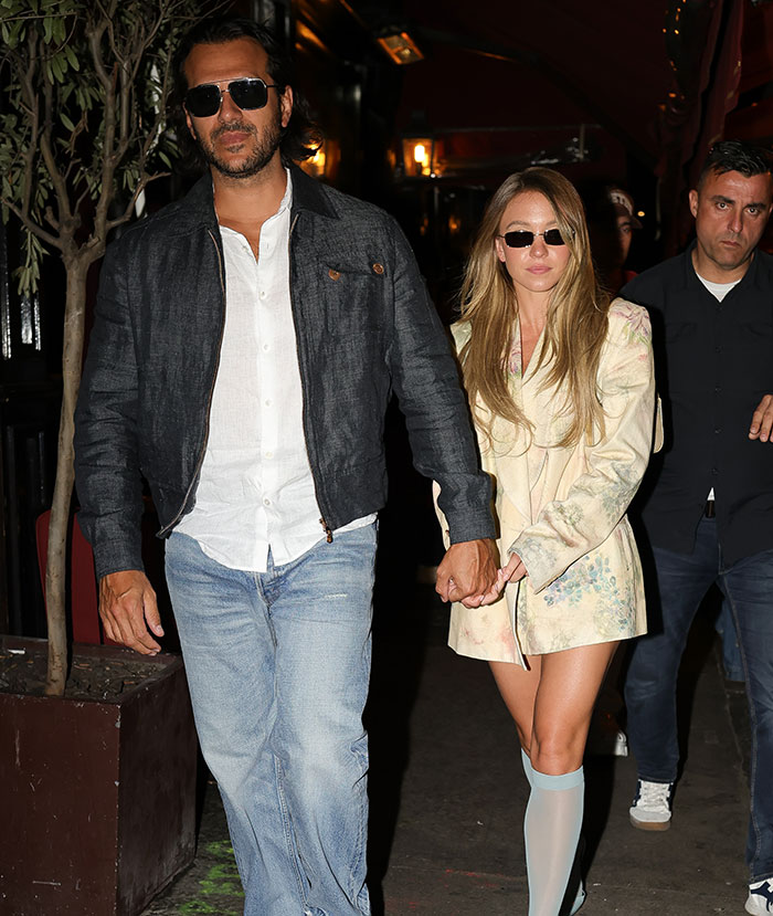 Man and woman holding hands at a night event, both wearing sunglasses and casual attire. Man and woman holding hands at a night event, both wearing sunglasses and casual attire.