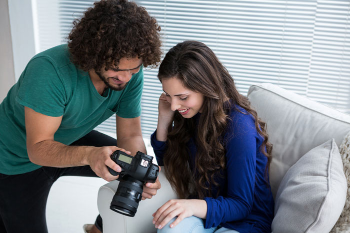 Woman with camera reviews engagement photos, focus on friendship dynamic. Woman with camera reviews engagement photos, focus on friendship dynamic.