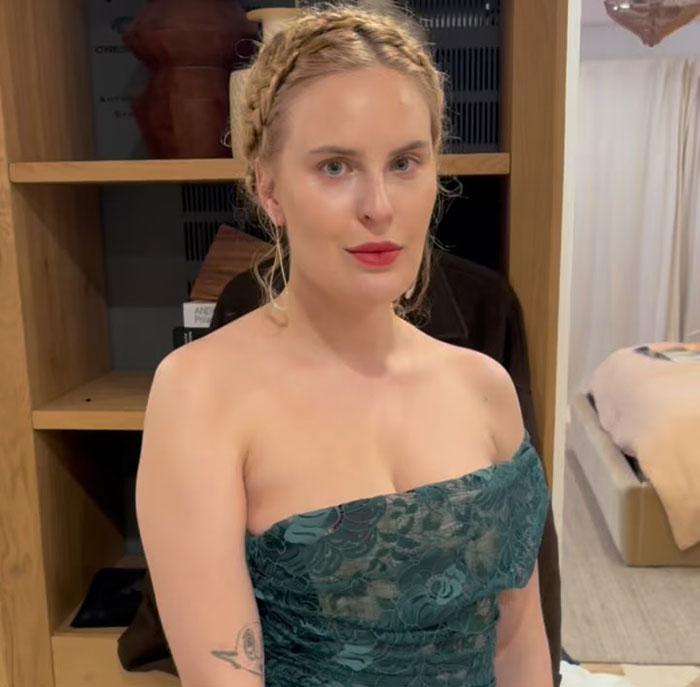 Demi Moore's daughter in a teal dress, standing in a room with a bookshelf and bed in the background. Demi Moore's daughter in a teal dress, standing in a room with a bookshelf and bed in the background.