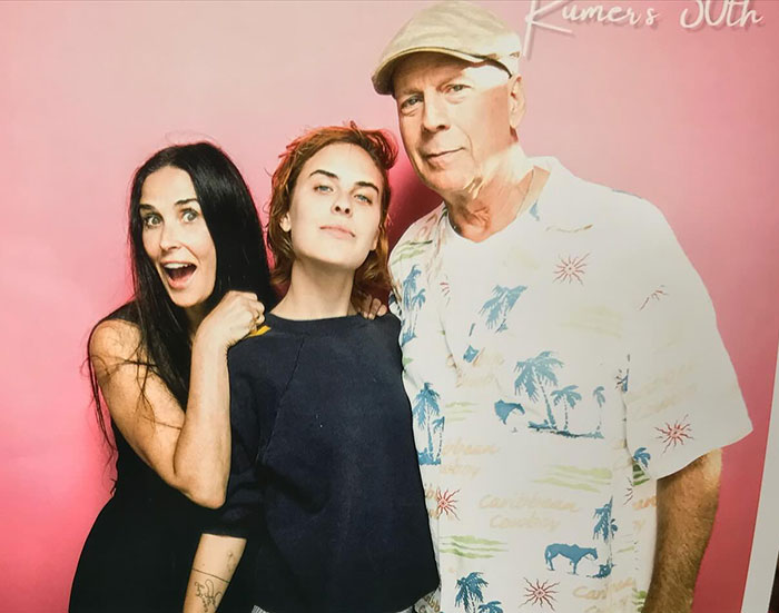 Demi Moore's daughter poses with family in front of a pink backdrop, smiling and casual. Demi Moore's daughter poses with family in front of a pink backdrop, smiling and casual.