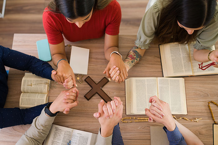 Group of people holding hands and praying over open Bibles with wooden cross, reflecting family drama and refusal to babysit. Group of people holding hands and praying over open Bibles with wooden cross, reflecting family drama and refusal to babysit.