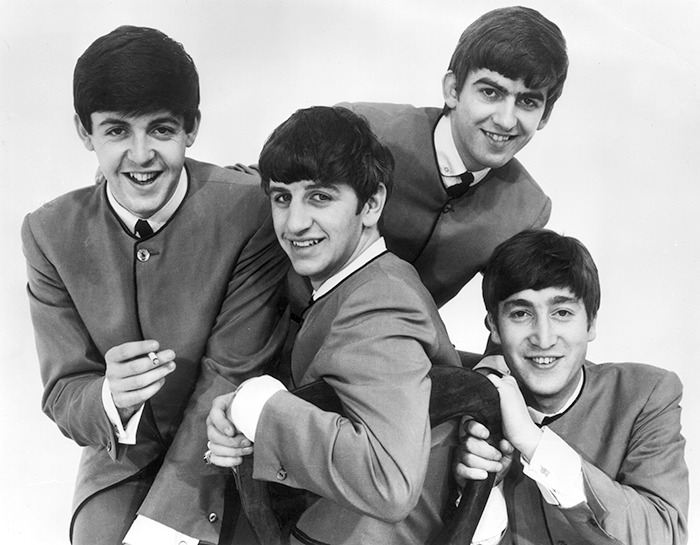 The Beatles posed together, smiling in classic suits, related to casting controversy. The Beatles posed together, smiling in classic suits, related to casting controversy.