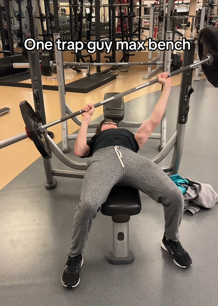 A young man bench pressing in a gym, displaying uneven muscle development by working out only one side of his body. A young man bench pressing in a gym, displaying uneven muscle development by working out only one side of his body.