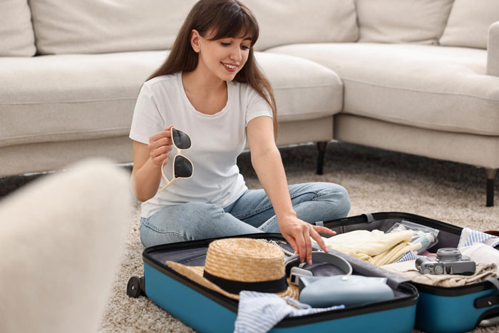 Woman packing a suitcase in a living room, organizing items for affordable flights travel. Woman packing a suitcase in a living room, organizing items for affordable flights travel.