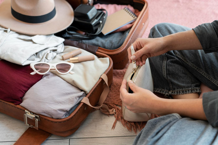 Person organizing a suitcase with clothes, hat, and camera, illustrating tips for affordable flights. Person organizing a suitcase with clothes, hat, and camera, illustrating tips for affordable flights.