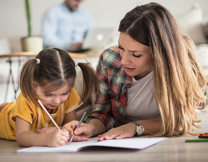 A mother helps her daughter with homework at home, focusing on learning and support. A mother helps her daughter with homework at home, focusing on learning and support.