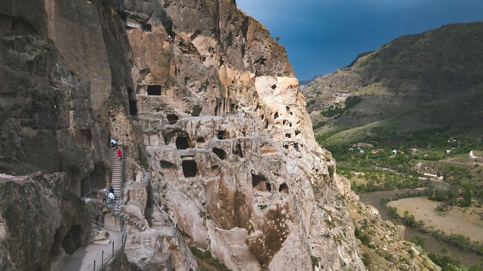 Cave dwellings carved into a cliffside, showcasing an eerie city built completely below ground.