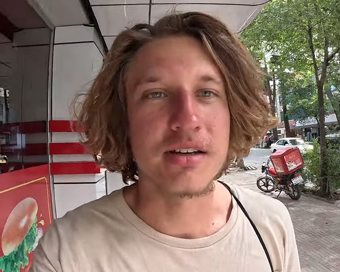 YouTuber outdoors on the street, wearing a beige shirt, related to isolated tribe stunt news. YouTuber outdoors on the street, wearing a beige shirt, related to isolated tribe stunt news.