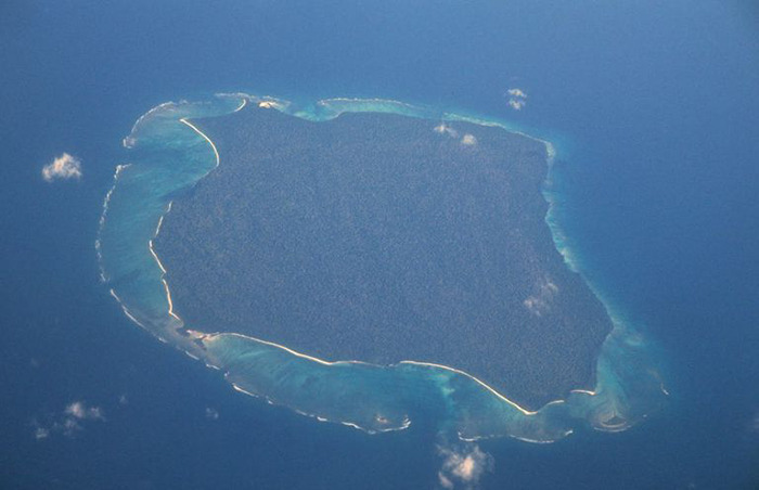 Aerial view of an isolated island surrounded by blue ocean, related to YouTuber facing jail for risking tribe's extinction. Aerial view of an isolated island surrounded by blue ocean, related to YouTuber facing jail for risking tribe's extinction.