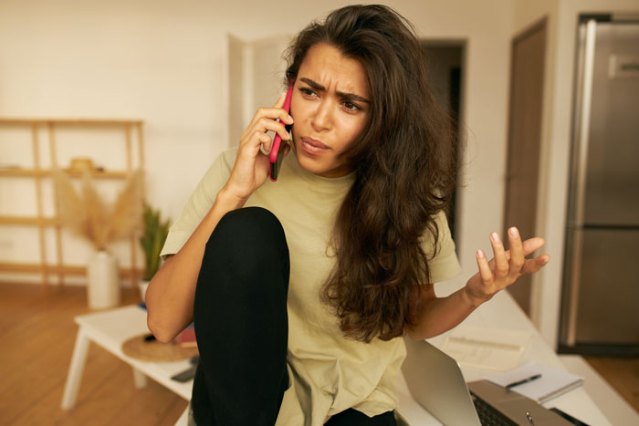 Woman on phone looking upset, involved in a discussion about a trip and wedding situation. Woman on phone looking upset, involved in a discussion about a trip and wedding situation.