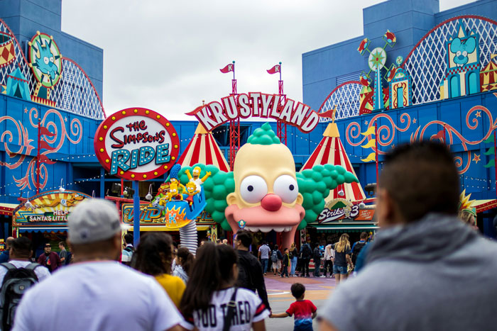 Crowd at a vibrant theme park entrance featuring The Simpsons Ride in the UK. Crowd at a vibrant theme park entrance featuring The Simpsons Ride in the UK.