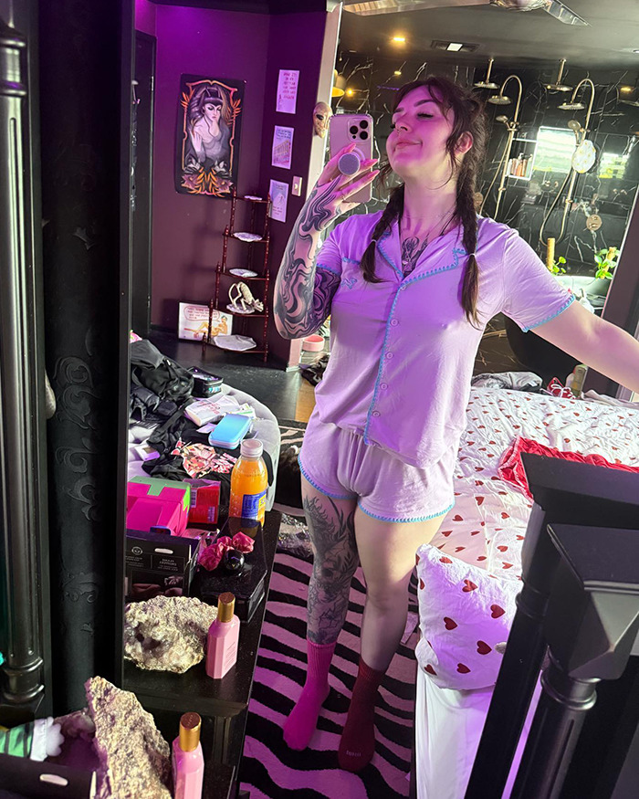 A woman with tattoos in a mirror selfie, surrounded by beauty products, sparking debate on waxing fees related to size. A woman with tattoos in a mirror selfie, surrounded by beauty products, sparking debate on waxing fees related to size.