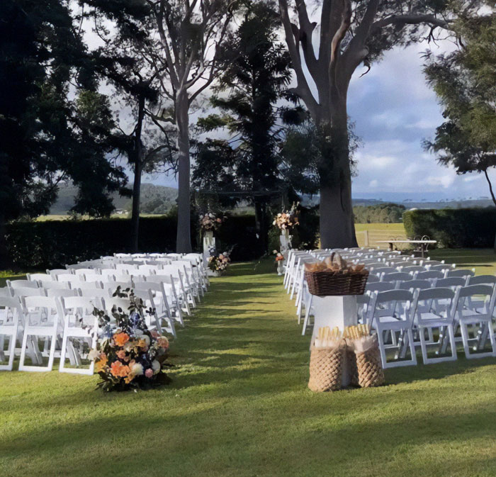 Wedding ceremony setup with white chairs, floral arrangements, and an outdoor backdrop; captures the stunning venue. Wedding ceremony setup with white chairs, floral arrangements, and an outdoor backdrop; captures the stunning venue.