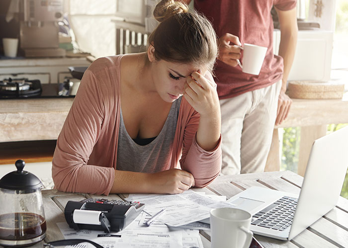 Wife tired from husband's false promises, stressed over bills at table with laptop and coffee. Wife tired from husband's false promises, stressed over bills at table with laptop and coffee.