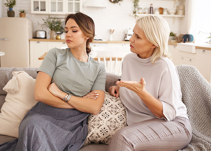 Pregnant woman ignoring overbearing MIL in living room argument. Pregnant woman ignoring overbearing MIL in living room argument.
