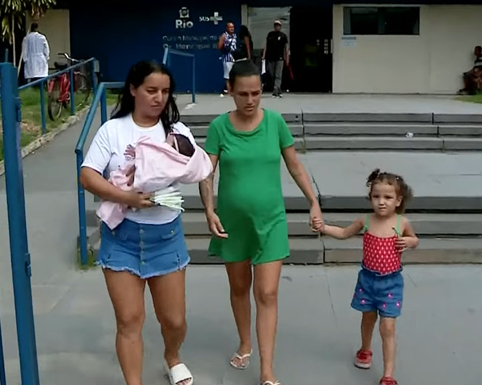 Pregnant woman with child and friend carrying baby outside hospital. Pregnant woman with child and friend carrying baby outside hospital.