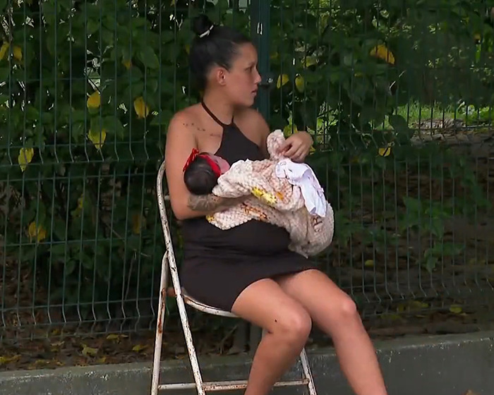 Pregnant woman holding one baby in her arms, sitting outdoors on a chair. Pregnant woman holding one baby in her arms, sitting outdoors on a chair.