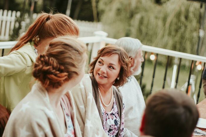 Women chatting outdoors, with one woman looking amused. Women chatting outdoors, with one woman looking amused.