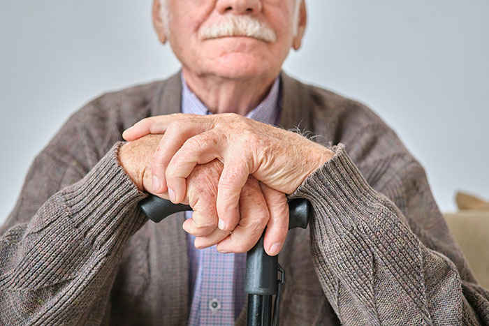 Elderly man with a cane, wearing a cardigan and sitting, representing family dynamics and complex father-daughter relationship. Elderly man with a cane, wearing a cardigan and sitting, representing family dynamics and complex father-daughter relationship.