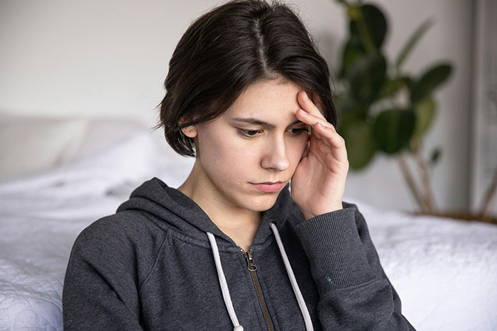 Woman looking concerned in a hoodie, thinking deeply, indoor setting, related to family and personal boundaries. Woman looking concerned in a hoodie, thinking deeply, indoor setting, related to family and personal boundaries.