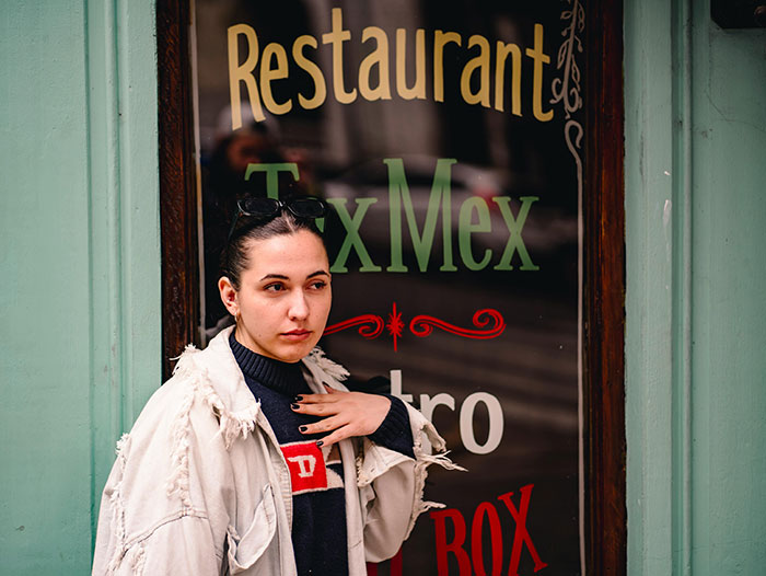 Woman in front of TexMex restaurant window, wearing a casual jacket, illustrating family food boundaries. Woman in front of TexMex restaurant window, wearing a casual jacket, illustrating family food boundaries.