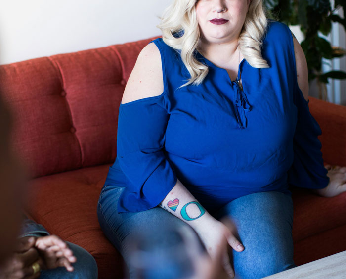 Obese woman in blue top sitting on a couch during a conversation about newborn babysitting and fat shaming. Obese woman in blue top sitting on a couch during a conversation about newborn babysitting and fat shaming.