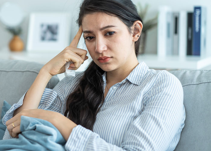 Sad woman sitting on couch looking thoughtful and upset, related to husband’s childhood best friend favor humiliation story. Sad woman sitting on couch looking thoughtful and upset, related to husband’s childhood best friend favor humiliation story.