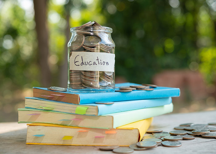 Jar labeled education filled with coins on a stack of books, symbolizing student loan collections impact on finances. Jar labeled education filled with coins on a stack of books, symbolizing student loan collections impact on finances.