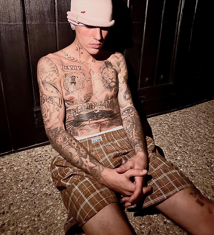 Justin Bieber shirtless in LA, showing tattoos and wearing a pink hat and brown checkered shorts at night. Justin Bieber shirtless in LA, showing tattoos and wearing a pink hat and brown checkered shorts at night.