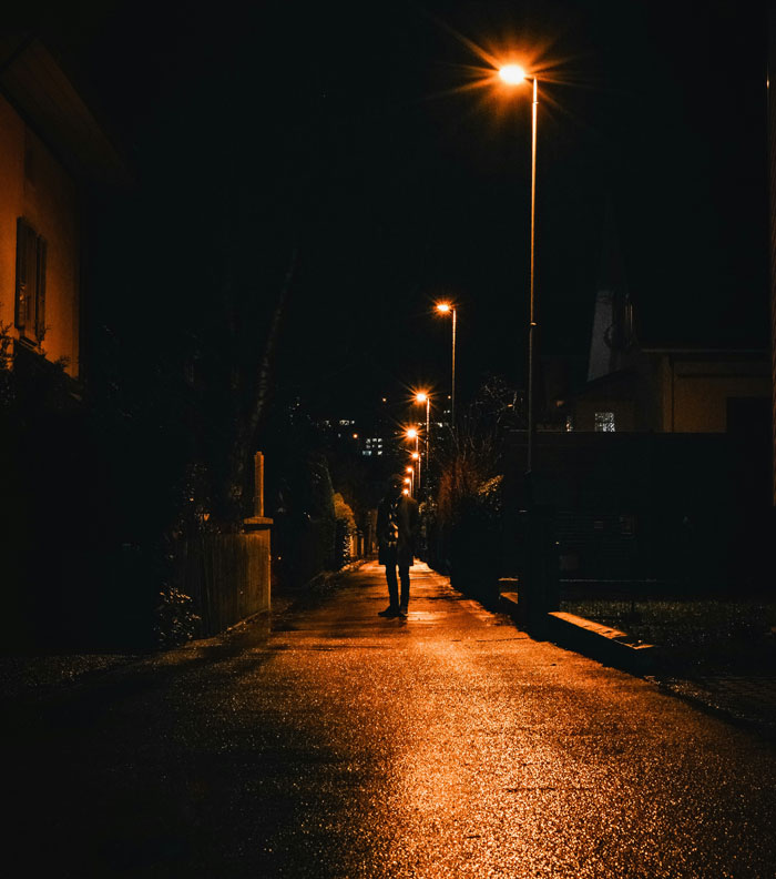 Person walking alone at night under streetlights, illustrating stories of strangers unsuccessfully attempting to mug them.