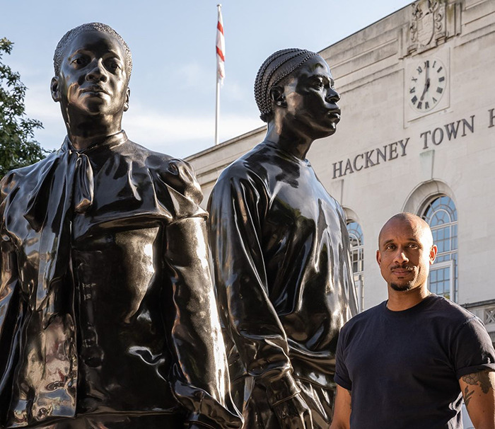 Statue of Black woman in NYC Times Square with man standing nearby, Hackney Town Hall in background during daytime. Statue of Black woman in NYC Times Square with man standing nearby, Hackney Town Hall in background during daytime.