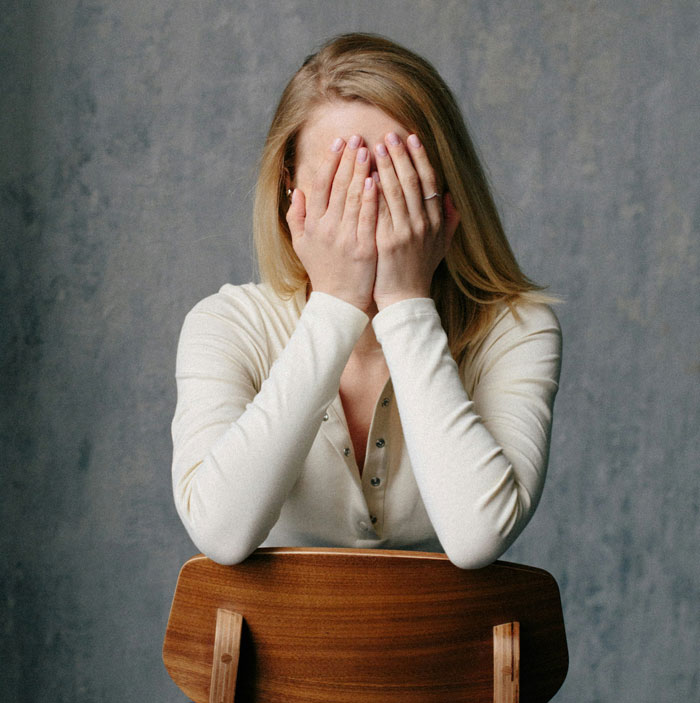 Woman covering her face in frustration, illustrating common reactions to infuriating things said by people in charge.