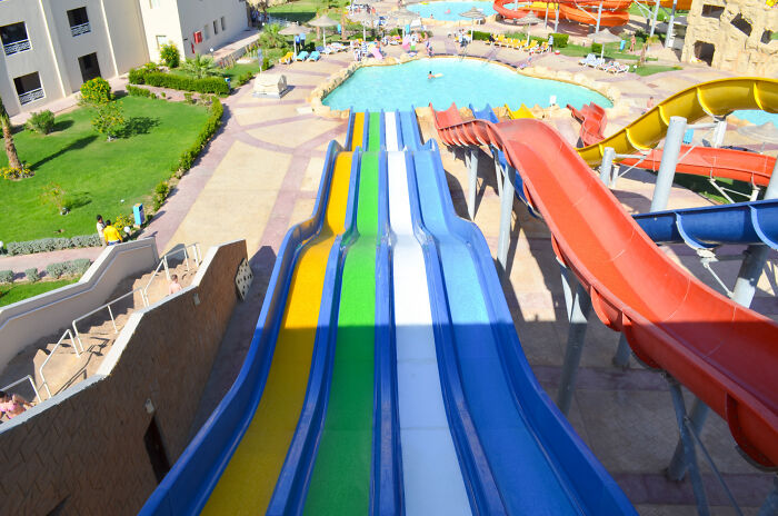 Colorful water slides at a busy water park with pools and people enjoying summer activities.