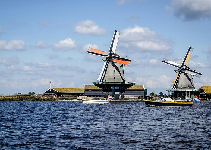 Traditional windmills near water with boats, illustrating unique aspects of living in home countries.