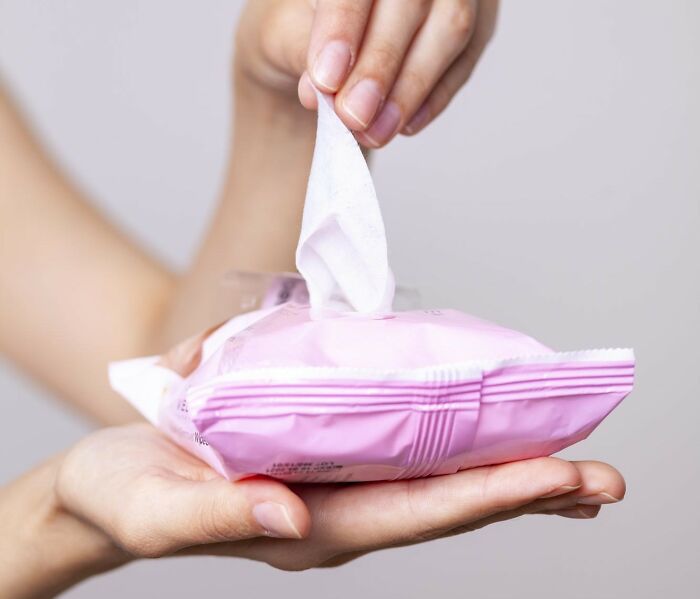 Hand pulling a wet wipe from a pink package, showing a tiny thing that made the trip better.
